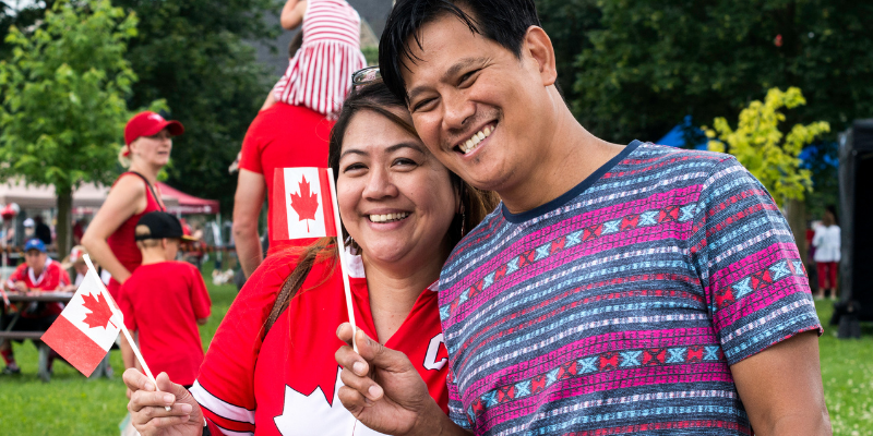 couple tenant des drapeaux du canada dans la main