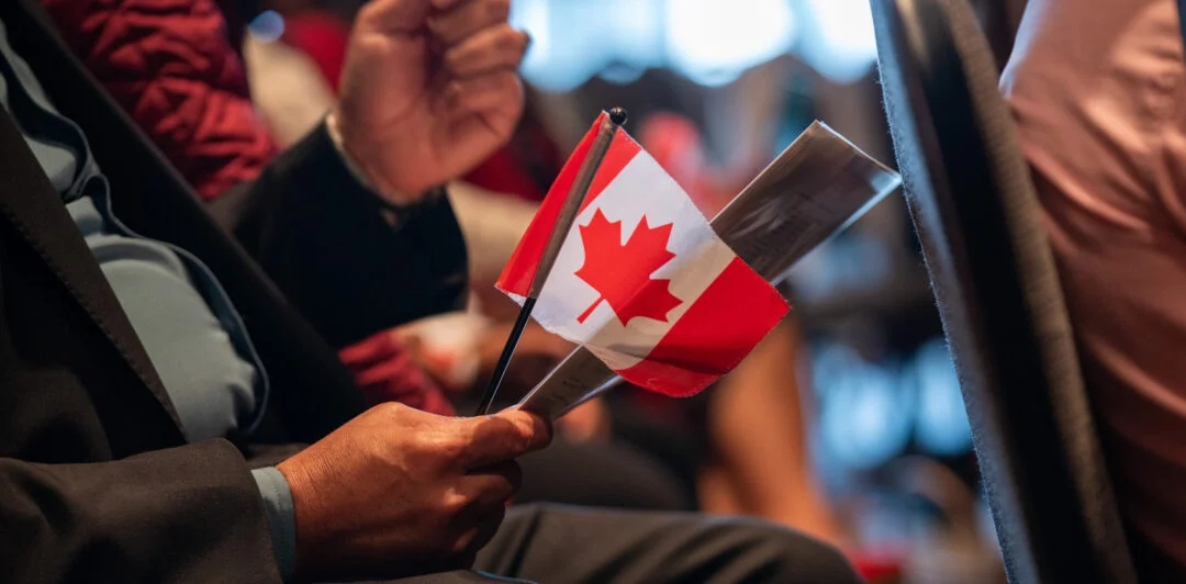 c&eacute;r&eacute;monie de citoyennet&eacute; canadienne avec un homme tenant un petit drapeau canadien dans la main